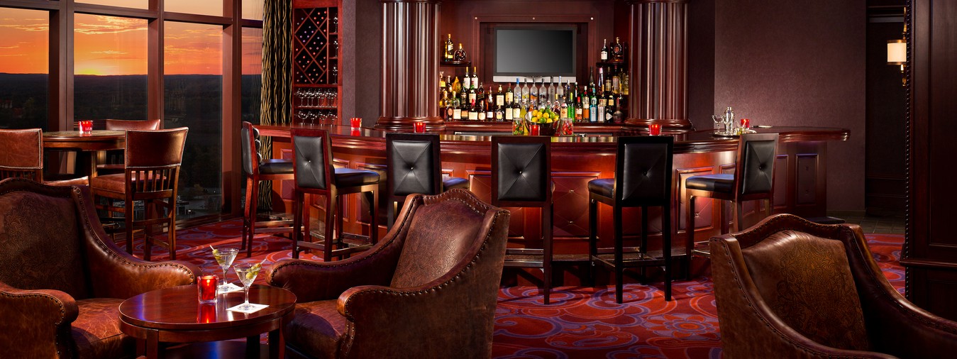 The upscale bar and dining area in TS Steakhouse with black leather bar seats and cozy brown leather dining chairs
