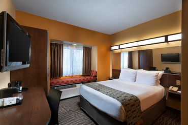 Room with one queen bed, a desk, television, and a window nook at Sandstone Hollow Inn