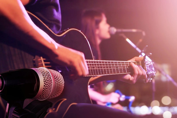 Close up of accoustic guitar being played on stage during a live concert performance in the showroom.