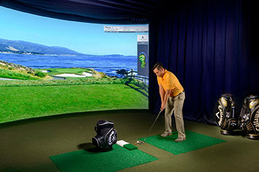 Man practices his golf drive on a virtual indoor driving range