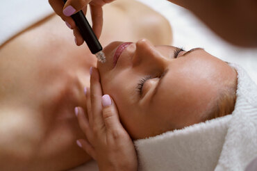 Woman receiving using hydrafacial device on face
