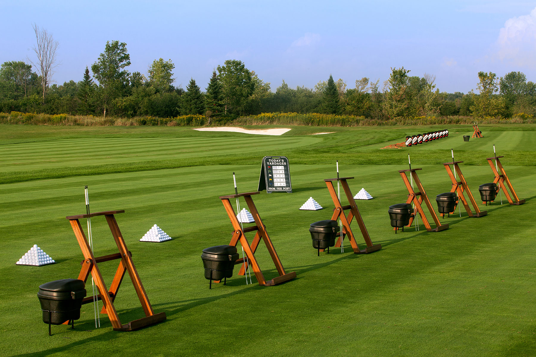 wide view of the golf warm up area with small pyramids of golf balls ready to be driven