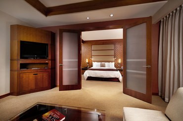 Wood-and-frosted French doors are open to reveal the luxurious living quarters in The Lodge suites with a king bed and soaking tub