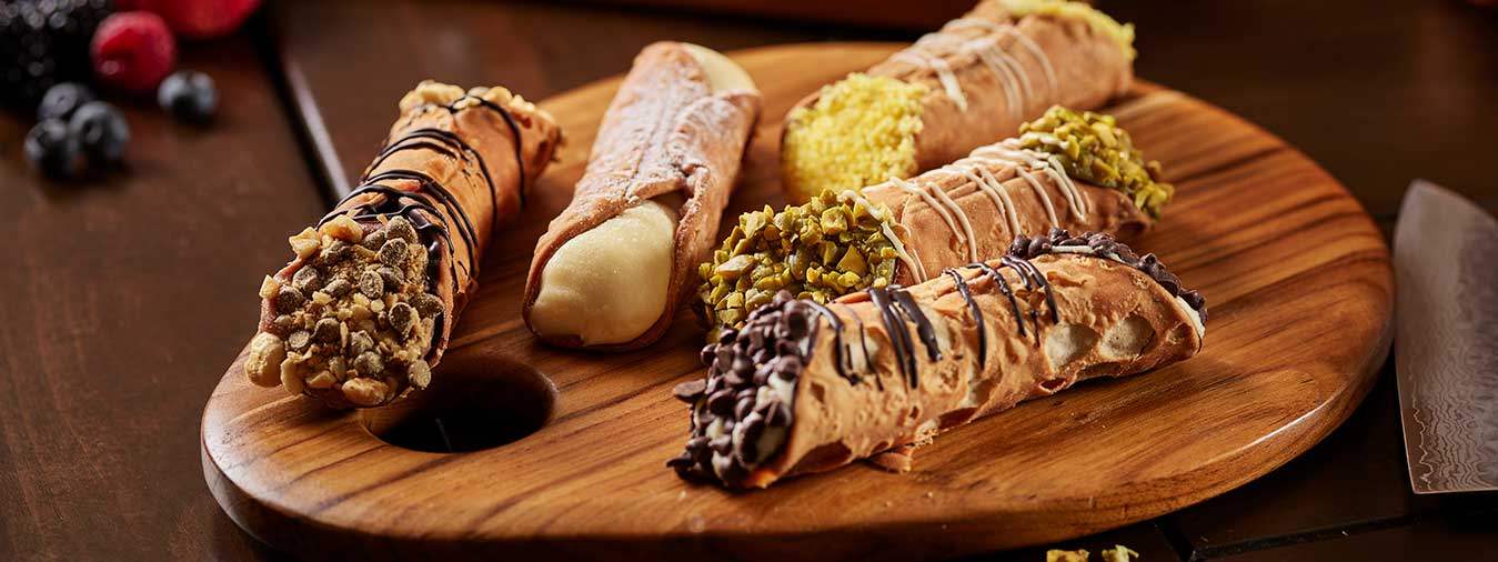 Assorted cannoli on wooden serving tray