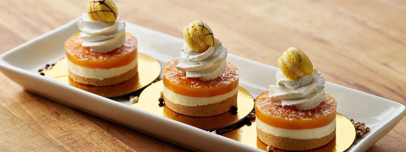 Mango pastry topped with whipped cream and yellow macaron