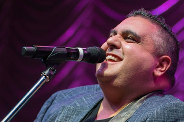 Bill Ali headshot performing at microphone