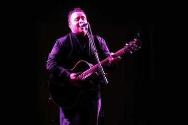 Gary Johnson performing at microphone with guitar