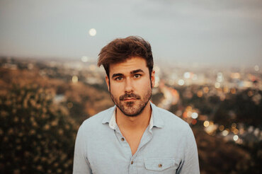Ryan Quinn headshot with blurred city background color