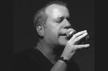 Mark Macri singing at microphone black and white