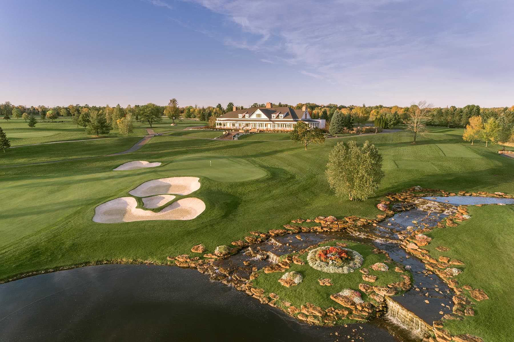 Panoramic view of Atunyote and Clubhouse with streams falling in to pond in evening sunlight