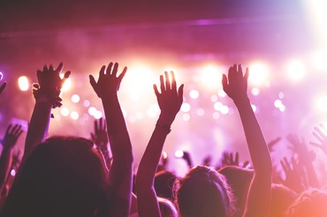 crowd with hands raised looking at stage